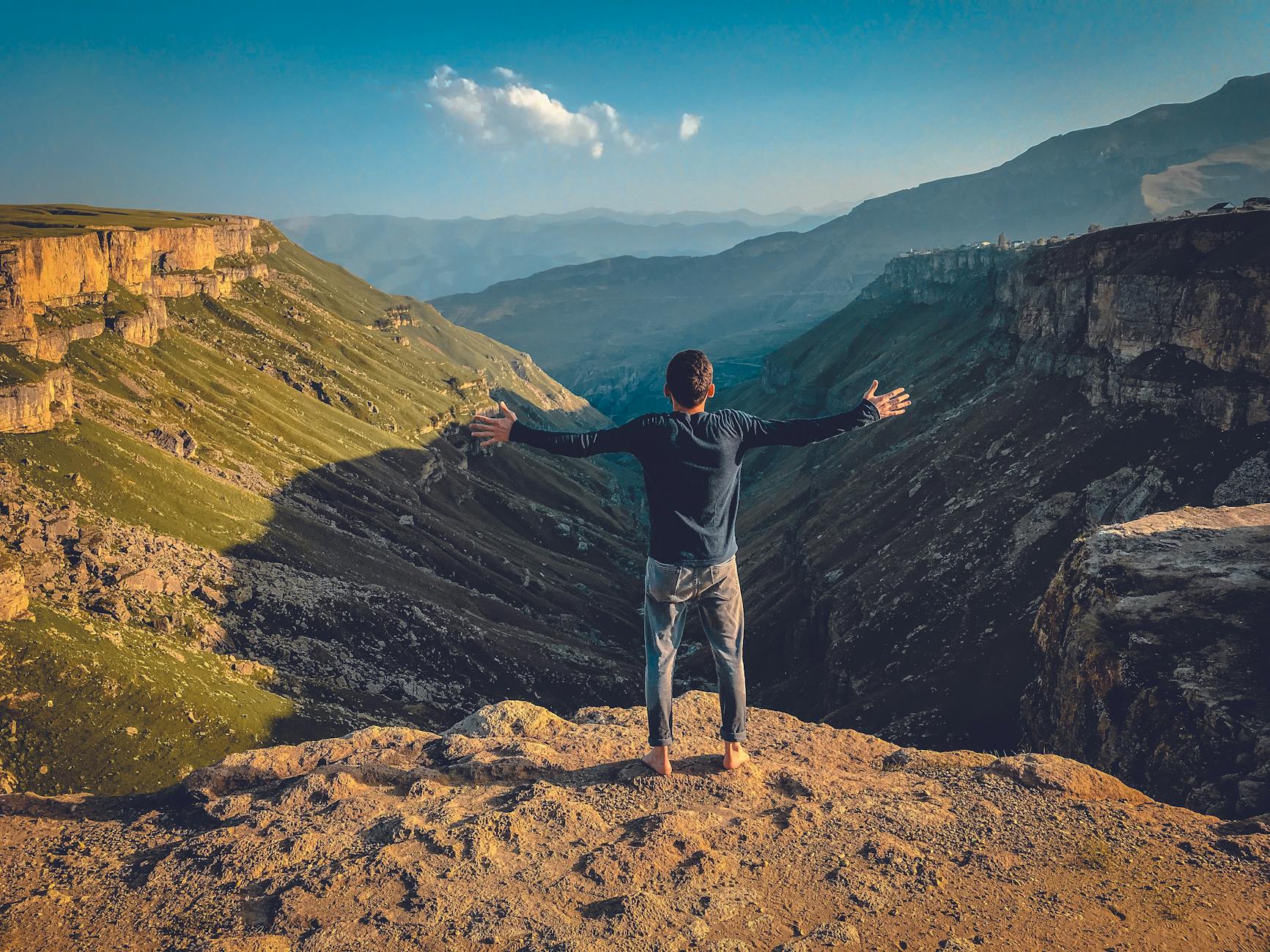 man standing on plateau with arms wide open