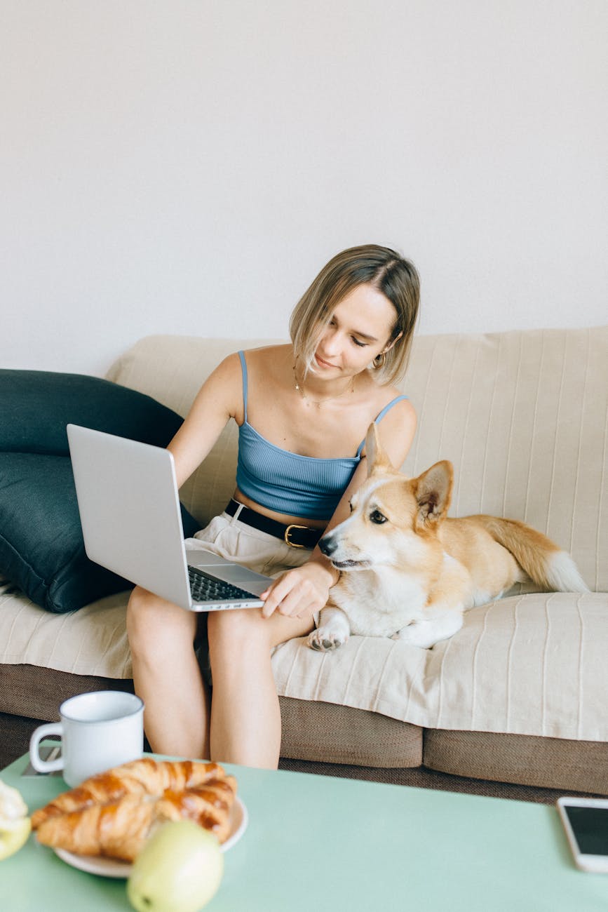 woman in blue tank top sitting on couch using macbook